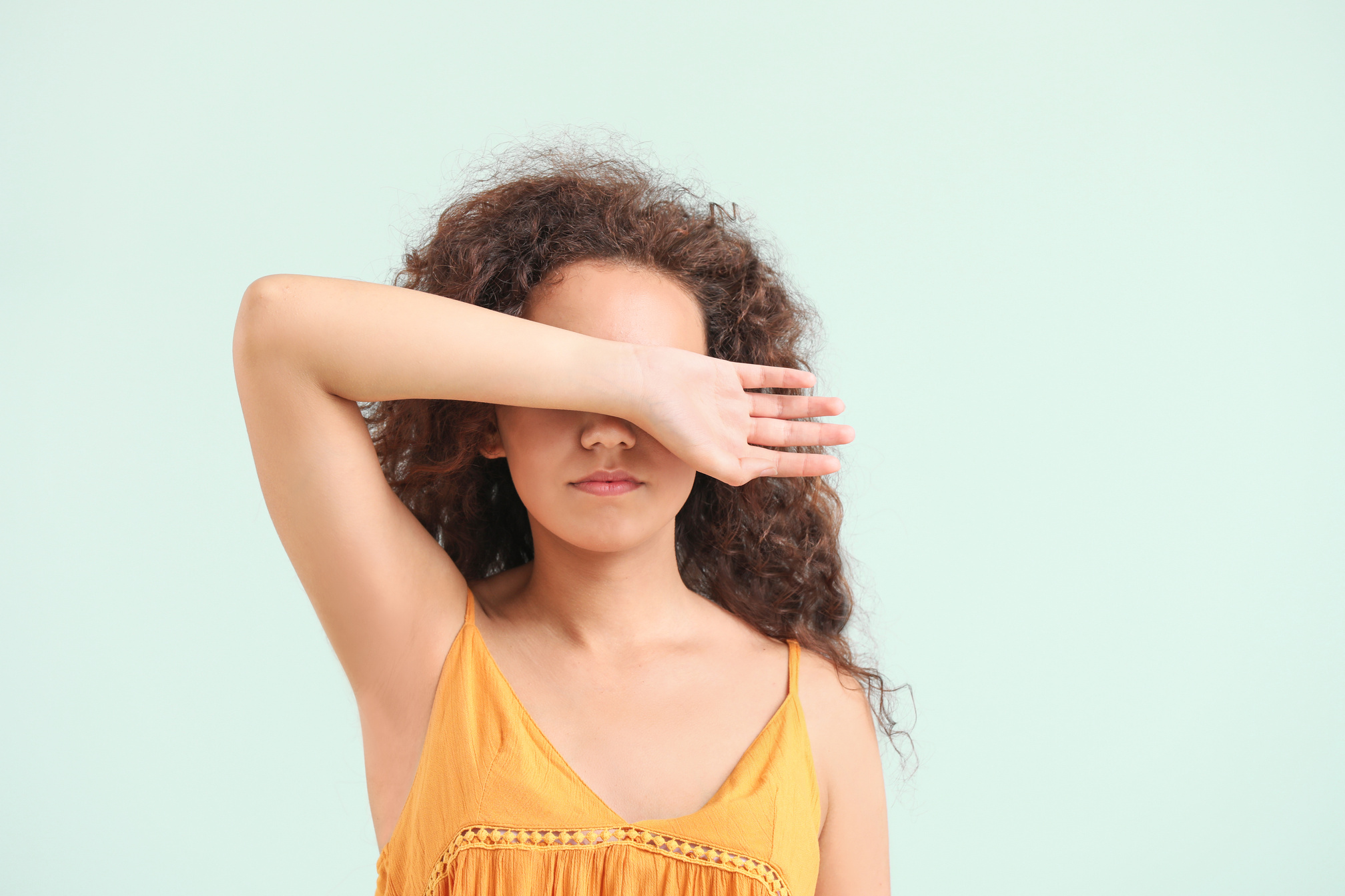 Young African-American Woman Covering Her Eyes on Light Background